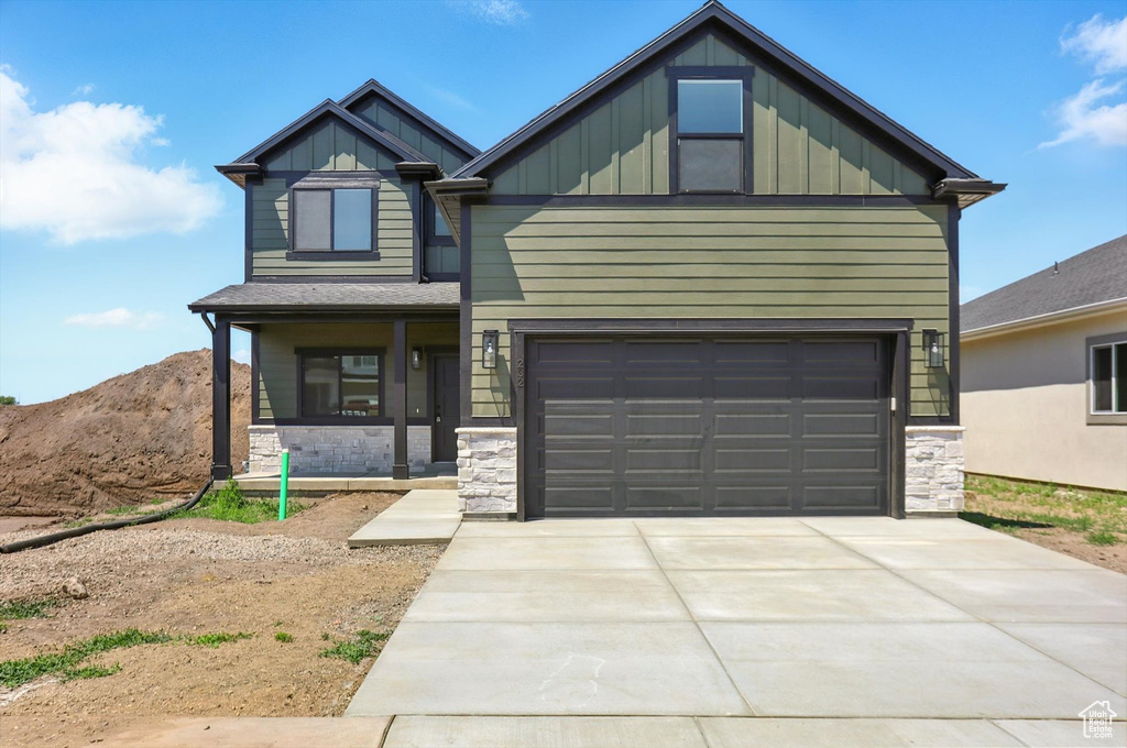 Craftsman-style house featuring board and batten siding, stone siding, an attached garage, and driveway