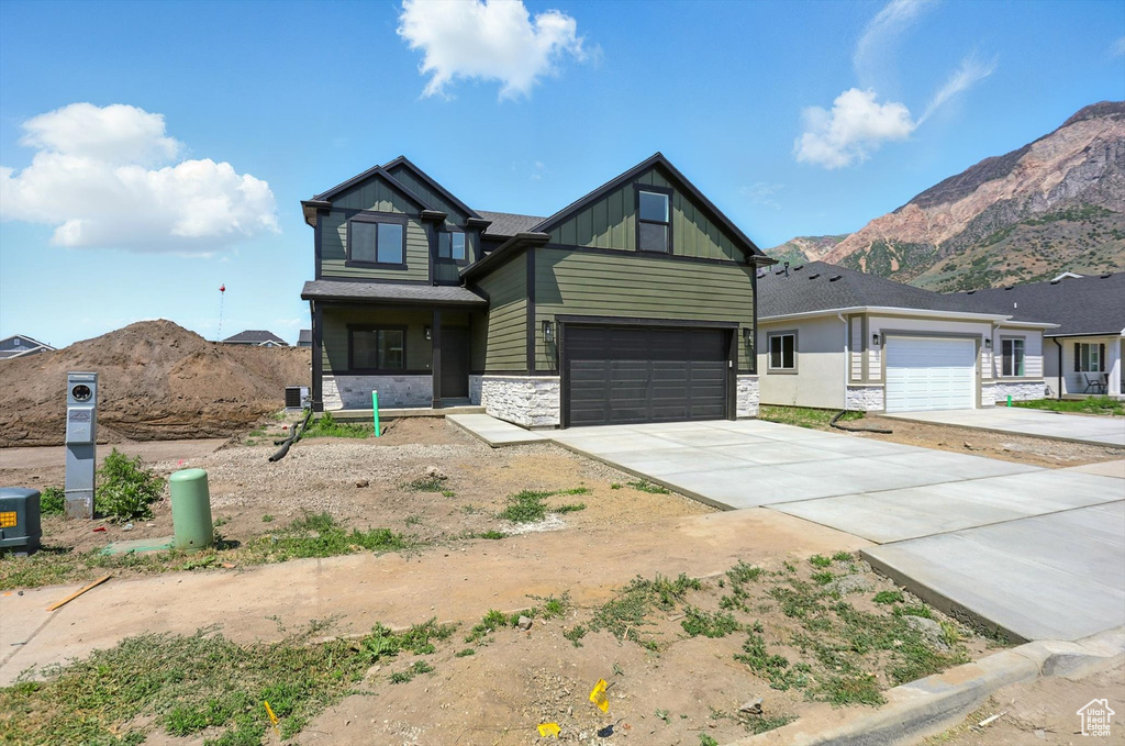 View of front of house with stone siding, driveway, a mountain view, and board and batten siding