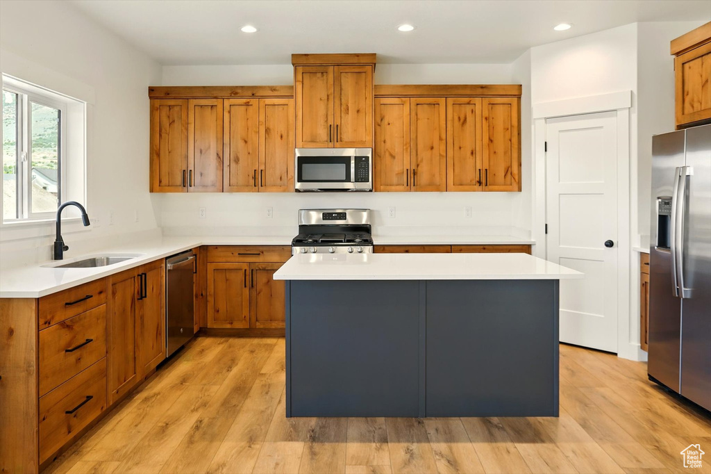 Kitchen featuring appliances with stainless steel finishes, brown cabinets, light countertops, recessed lighting, and a kitchen island