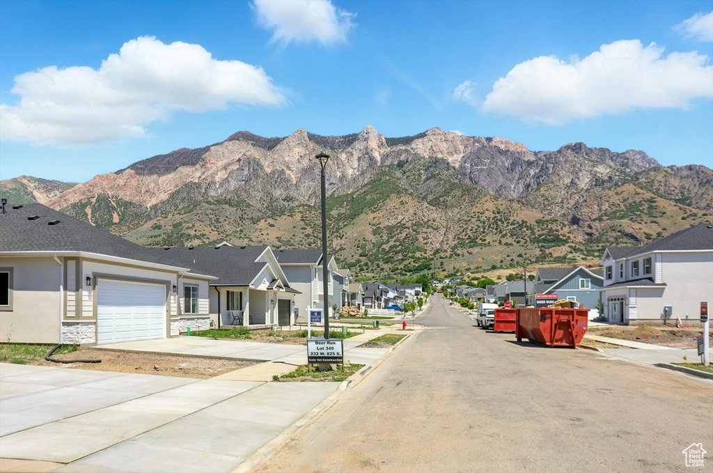 View of asphalt street with a residential view, street lighting, a mountain view, and sidewalks