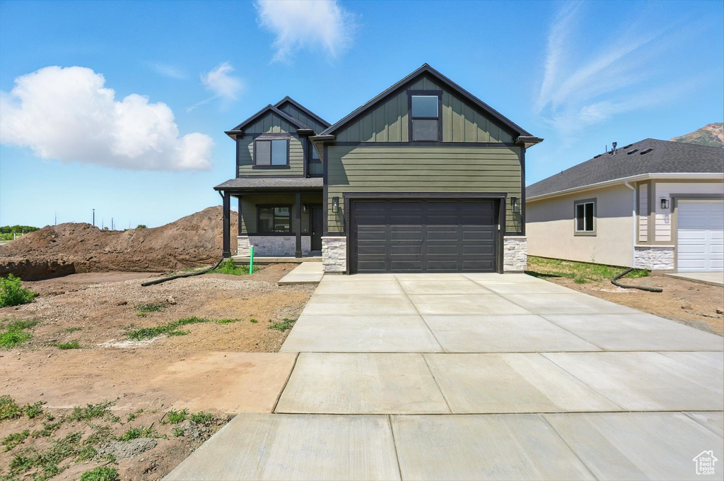 Craftsman-style home featuring stone siding, board and batten siding, concrete driveway, and an attached garage