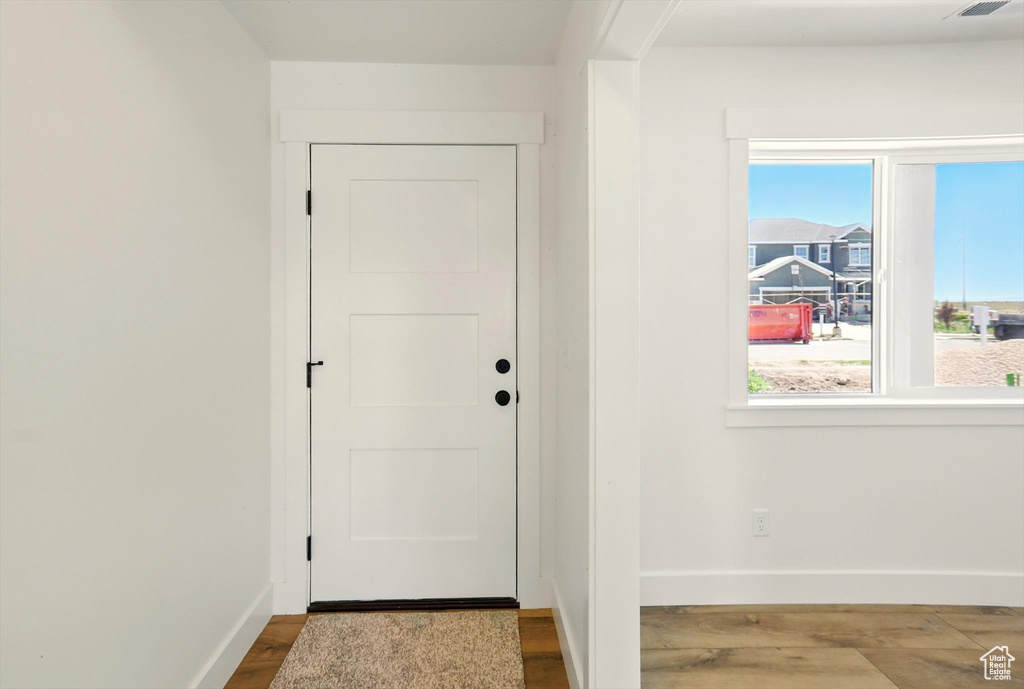 Doorway with baseboards and wood finished floors