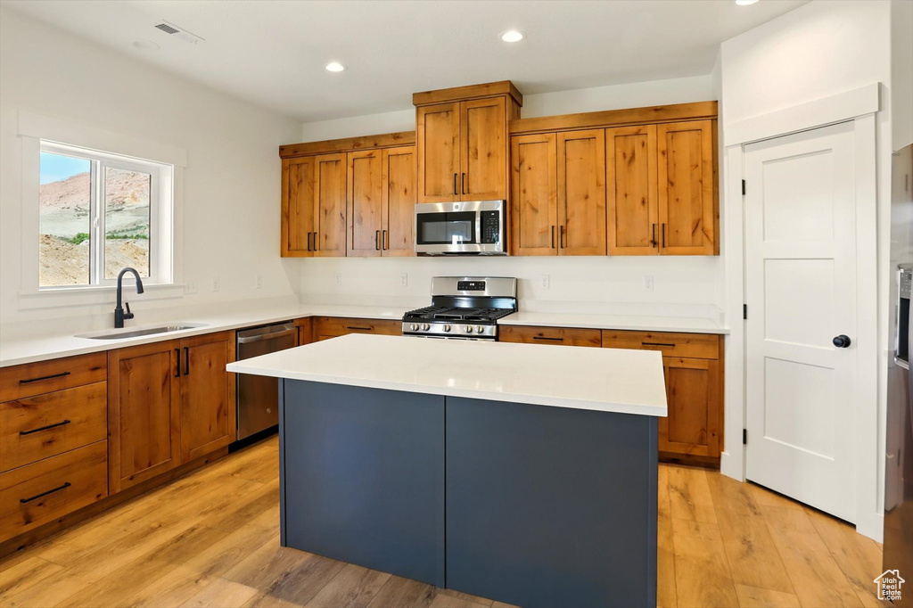 Kitchen with appliances with stainless steel finishes, brown cabinets, light wood-style flooring, light countertops, and recessed lighting