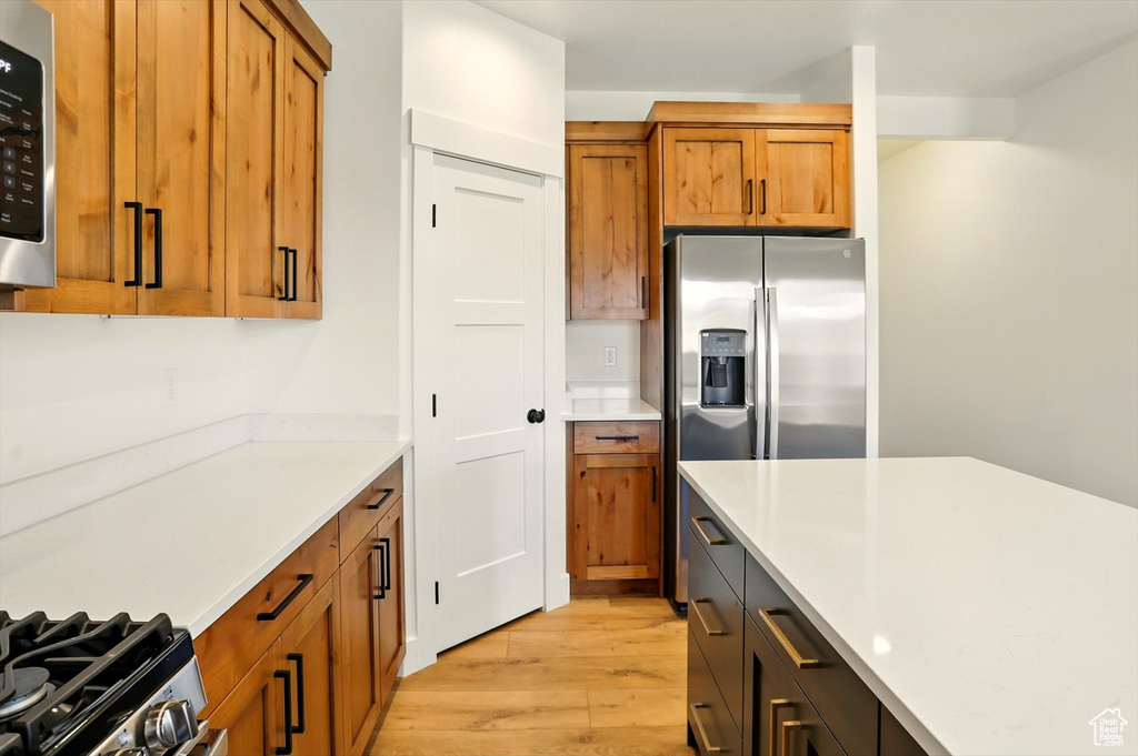 Kitchen with light wood-style flooring, brown cabinets, light countertops, and stainless steel appliances