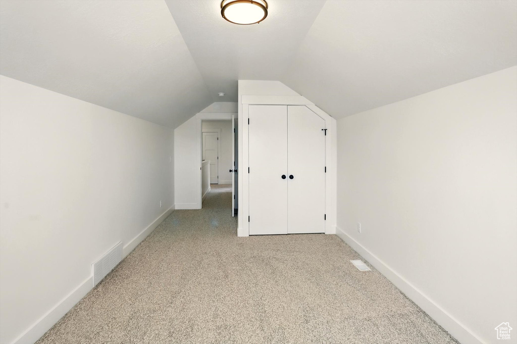 Additional living space with light carpet and lofted ceiling