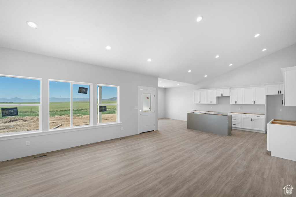 Kitchen with white cabinets, a center island, light wood-type flooring, open floor plan, and recessed lighting