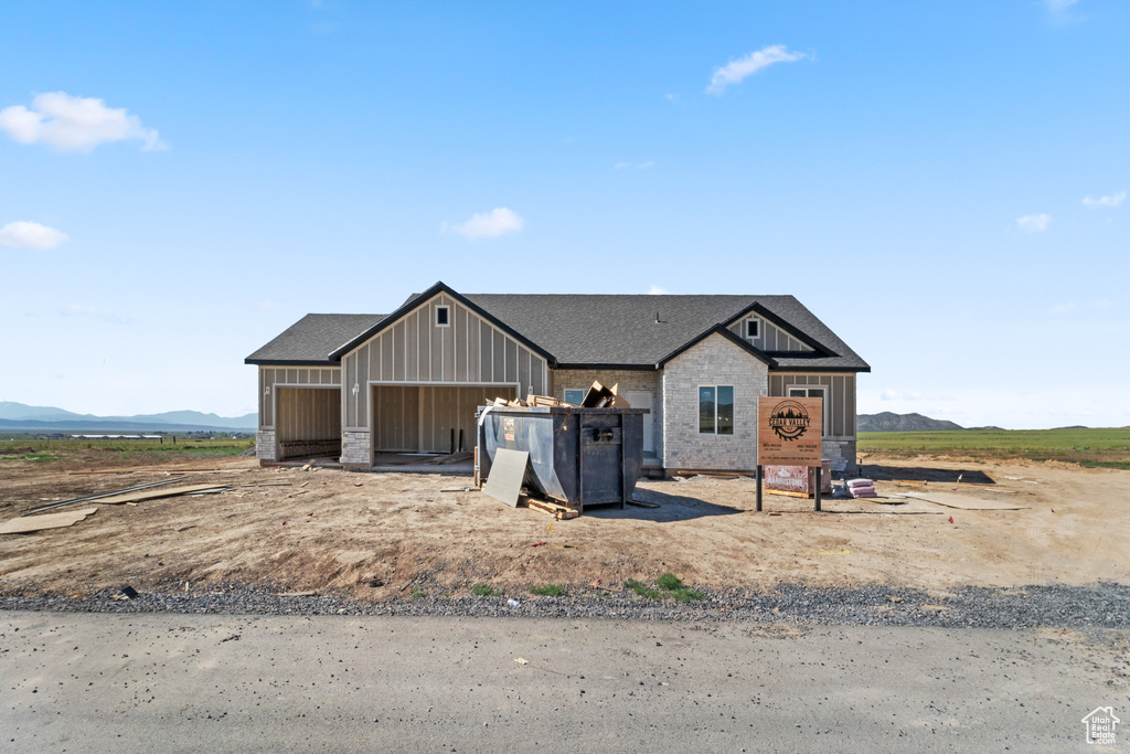 View of front of property with a mountain view, a garage, roof with shingles, and board and batten siding