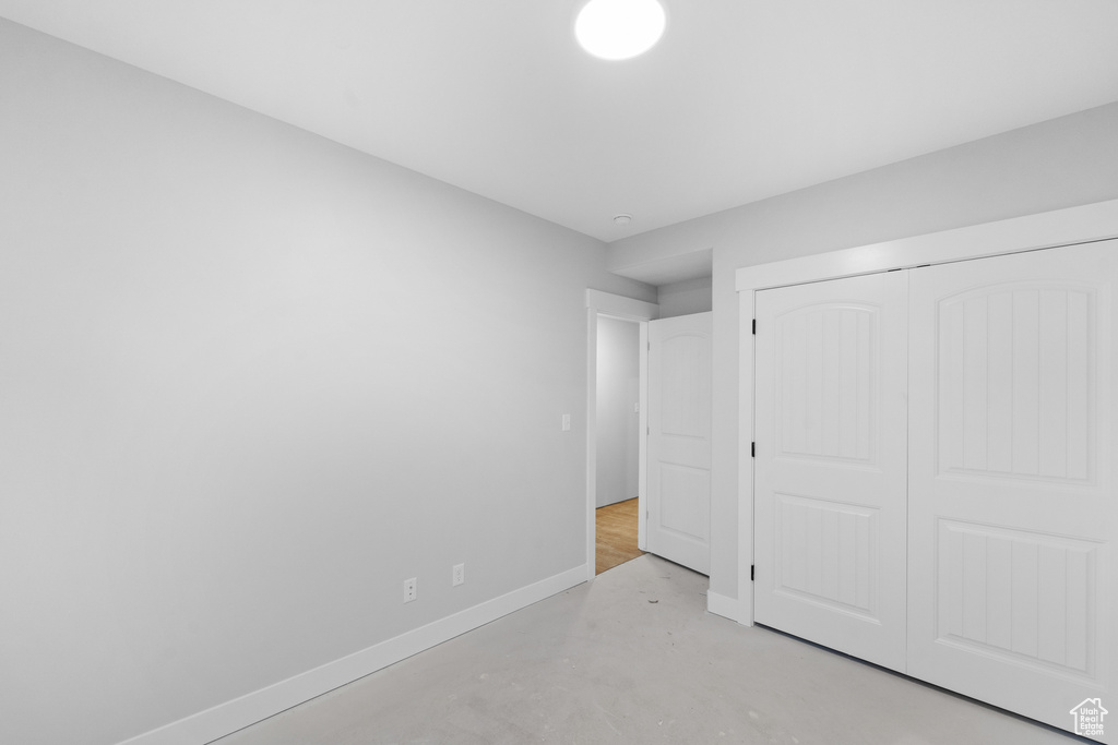 Unfurnished bedroom with concrete floors and a closet