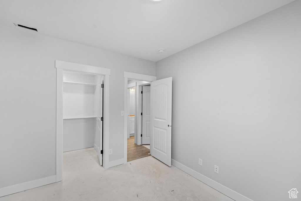 Unfurnished bedroom featuring a spacious closet, concrete floors, and a closet