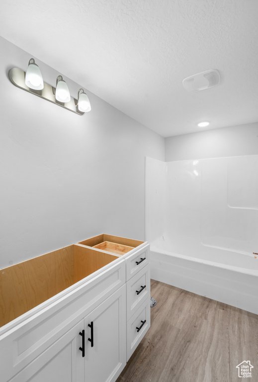 Bathroom featuring wood finished floors,  shower combination, and vanity