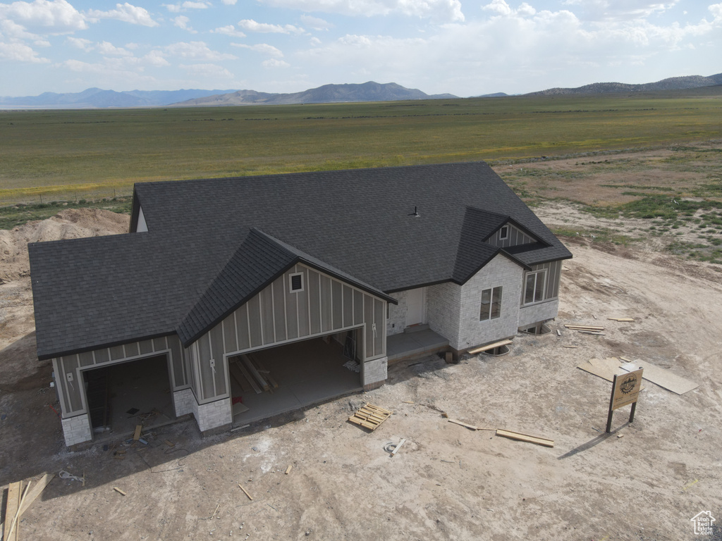 View of front of property featuring driveway, a rural view, board and batten siding, and a shingled roof