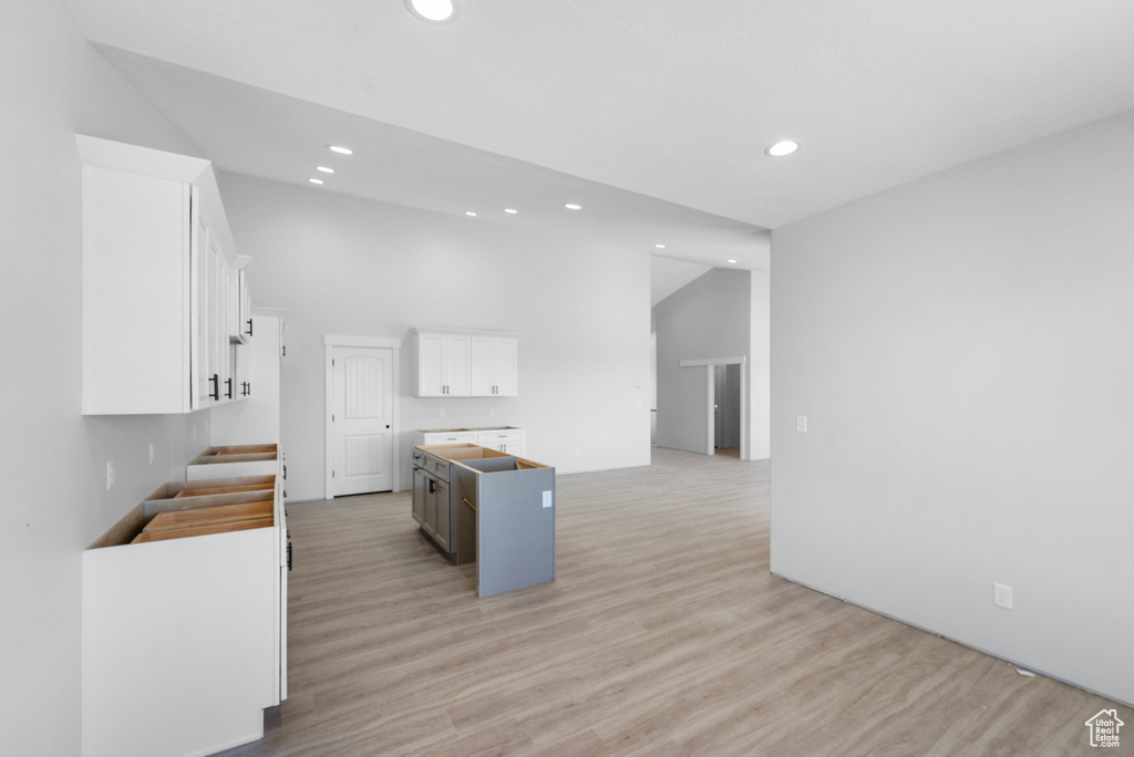 Kitchen featuring recessed lighting, light wood-style floors, a center island with sink, white cabinetry, and open floor plan