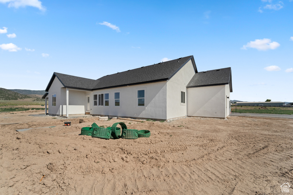 Back of property with stucco siding and roof with shingles