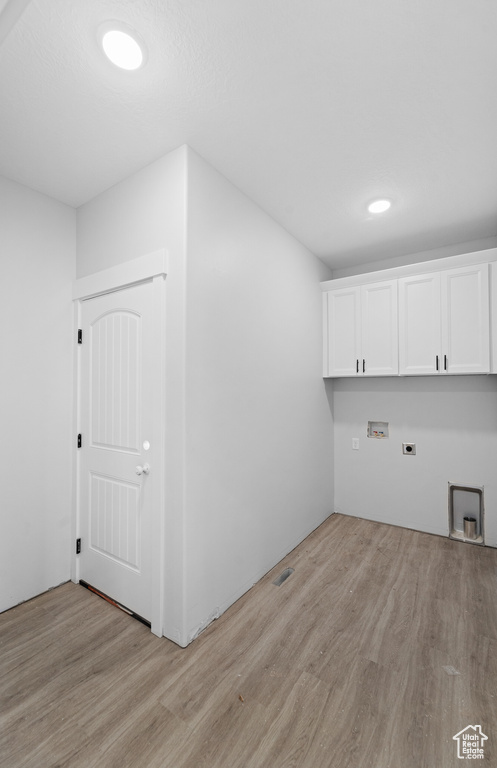 Laundry room with cabinet space, light wood-style flooring, hookup for an electric dryer, and hookup for a washing machine