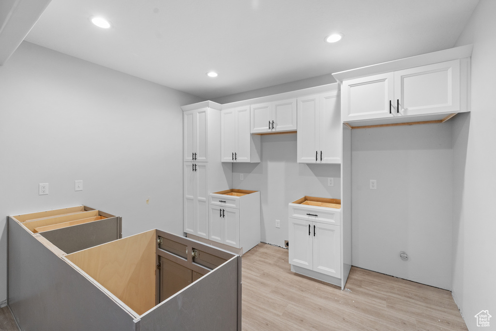 Kitchen with light wood-type flooring, white cabinets, and recessed lighting