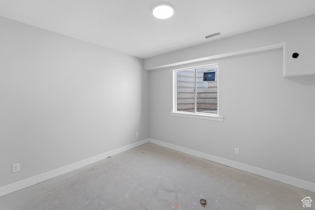 Spare room featuring unfinished concrete flooring and baseboards