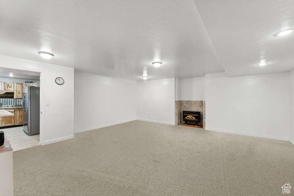 Unfurnished living room featuring a fireplace with flush hearth and light carpet