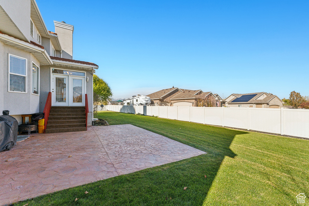 View of yard featuring a patio, a residential view, entry steps, and french doors