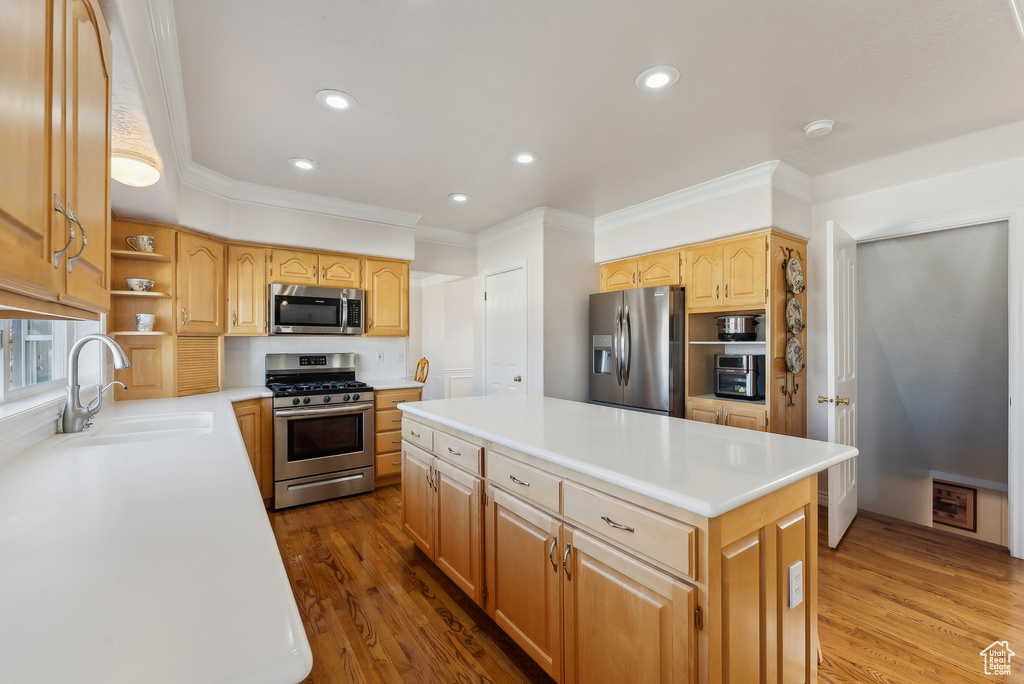 Kitchen with stainless steel appliances, crown molding, a kitchen island, wood finished floors, and open shelves