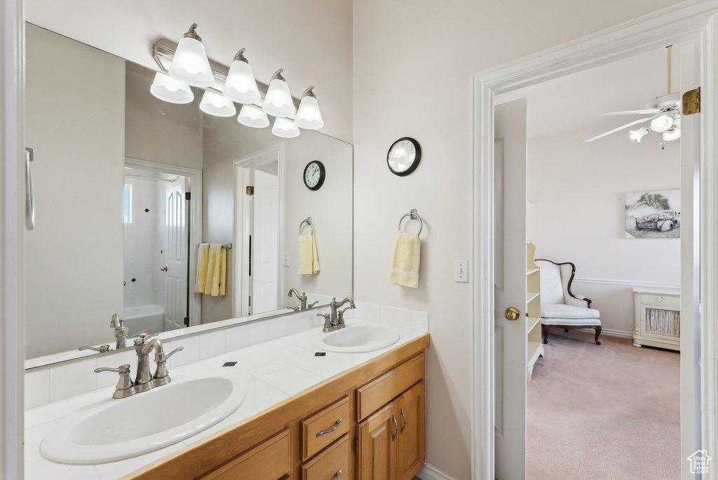 Full bath featuring double vanity, a ceiling fan, and shower / bathtub combination