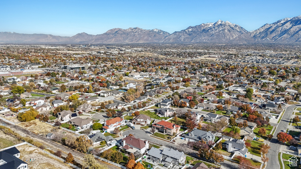 Aerial view of property and surrounding area featuring a mountain backdrop and nearby suburban area