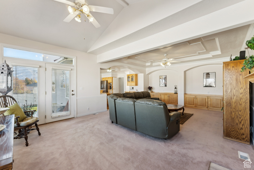 Living room with ceiling fan, light carpet, arched walkways, and vaulted ceiling