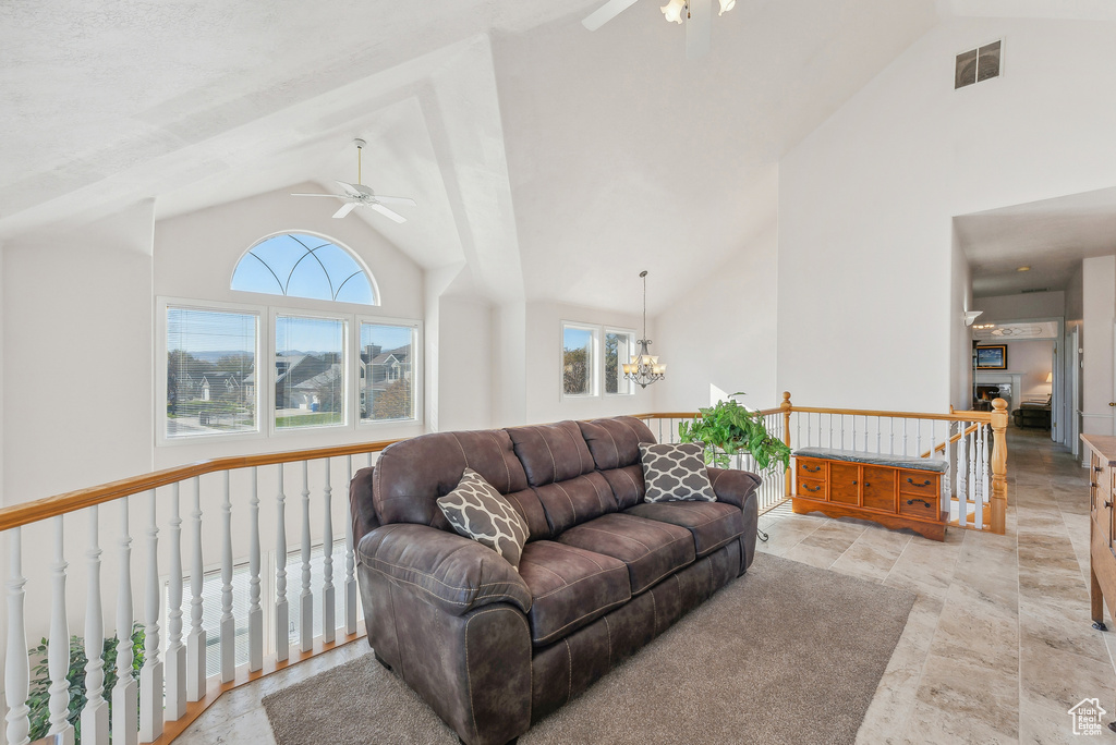 Living area featuring a ceiling fan, a chandelier, and high vaulted ceiling