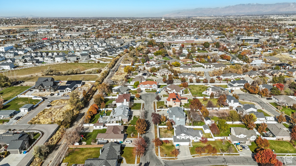 Aerial view of property and surrounding area featuring mountains and nearby suburban area