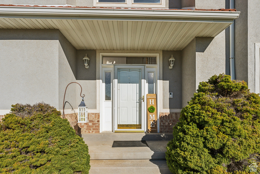 Entrance to property featuring stucco siding, stone siding, and a porch