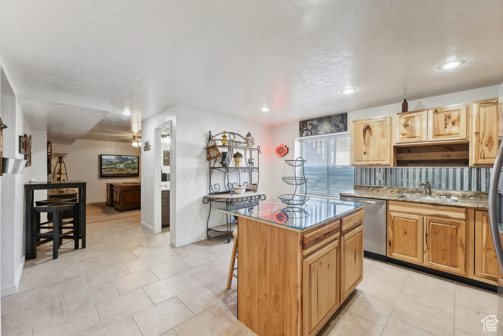 Kitchen featuring stainless steel dishwasher, a center island, recessed lighting, a breakfast bar area, and light tile patterned floors