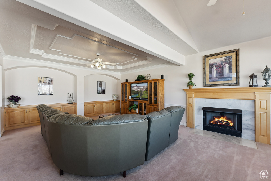 Living area with a ceiling fan, light colored carpet, crown molding, a raised ceiling, and a fireplace