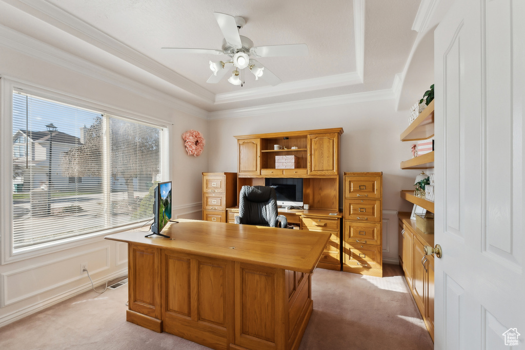 Office space with a ceiling fan, light carpet, a tray ceiling, ornamental molding, and wainscoting