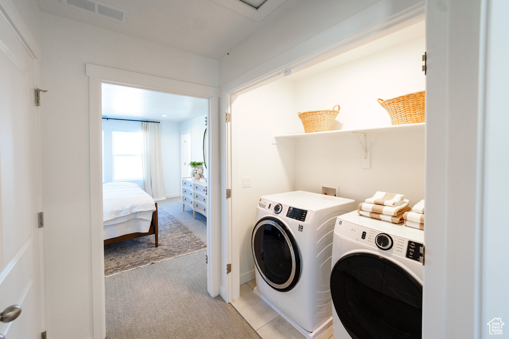 Laundry room with separate washer and dryer and light carpet