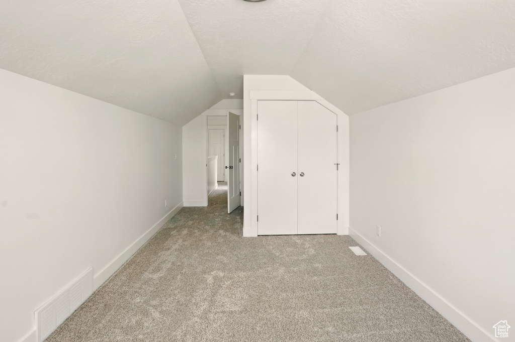 Additional living space with light carpet and lofted ceiling