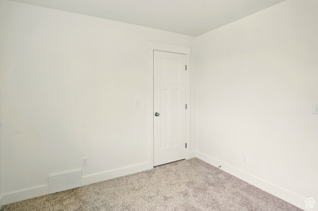 Empty room featuring light colored carpet and baseboards