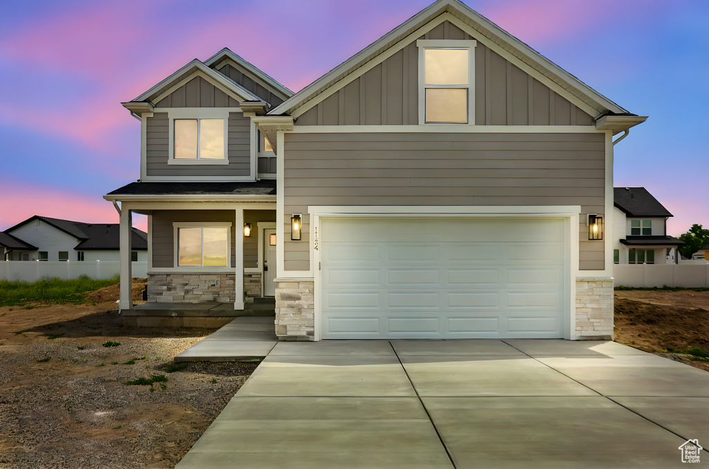 Craftsman inspired home with stone siding, board and batten siding, a porch, concrete driveway, and an attached garage