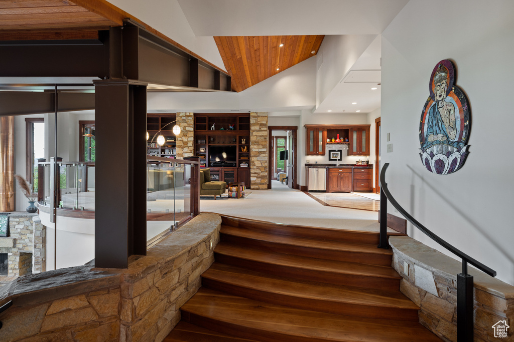Staircase featuring wood finished floors, built in shelves, wood ceiling, high vaulted ceiling, and recessed lighting