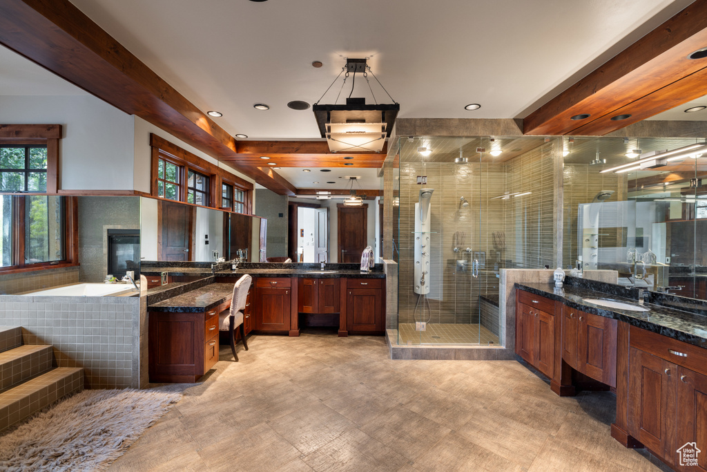 Full bathroom featuring a stall shower, two vanities, a garden tub, and a glass covered fireplace