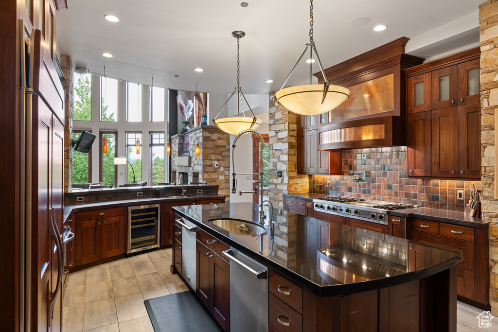 Kitchen with stainless steel appliances, beverage cooler, a sink, a kitchen island with sink, and decorative backsplash