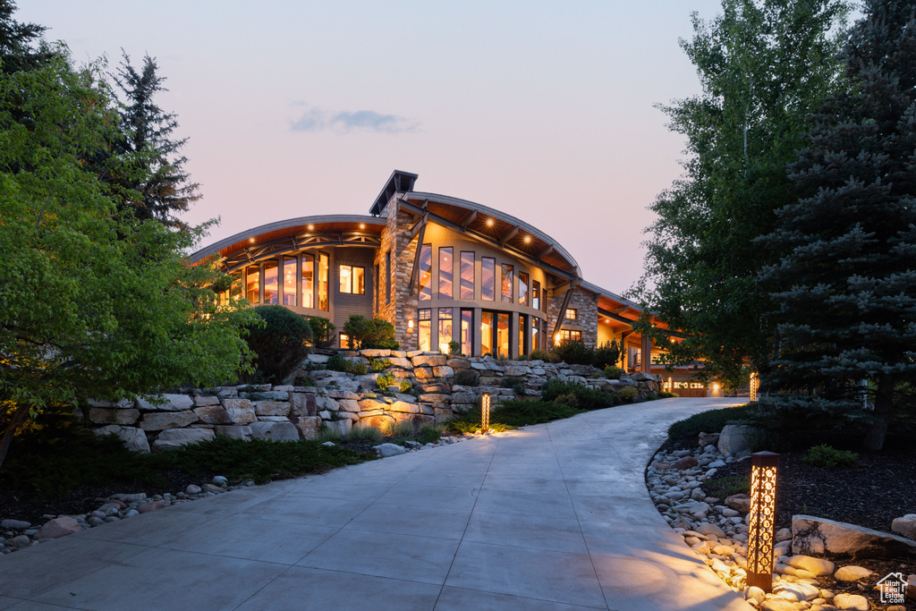 View of front facade with curved driveway and stone siding