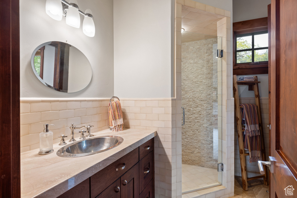 Bathroom featuring vanity, a stall shower, tile walls, and wainscoting