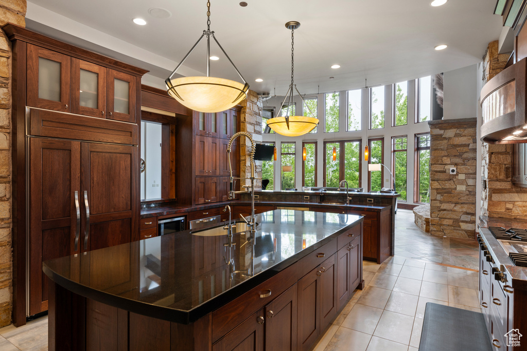 Kitchen featuring a large island, recessed lighting, a sink, hanging light fixtures, and glass insert cabinets