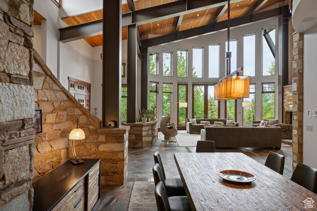 Dining room with high vaulted ceiling, wooden ceiling with exposed beams, and stone tile flooring