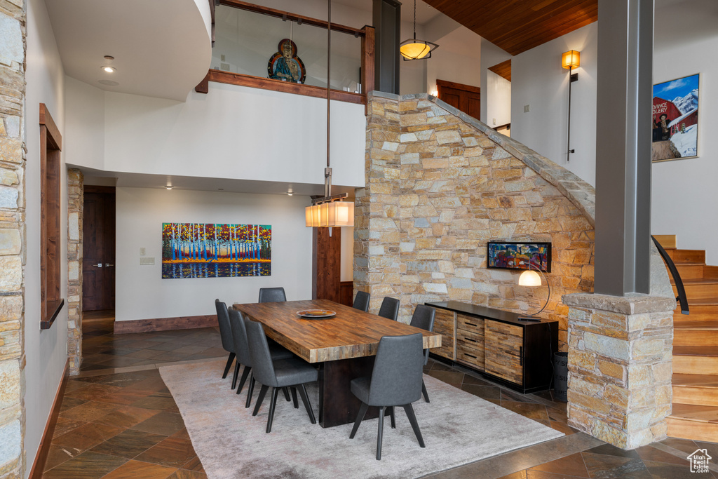 Dining space with a towering ceiling, stairway, recessed lighting, stone tile floors, and baseboards