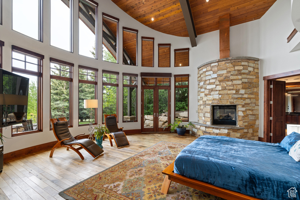 Bedroom featuring wood ceiling, high vaulted ceiling, wood-type flooring, a fireplace, and baseboards