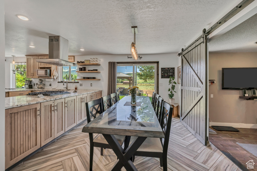 Dining room featuring a barn door, healthy amount of natural light, a textured ceiling, and recessed lighting