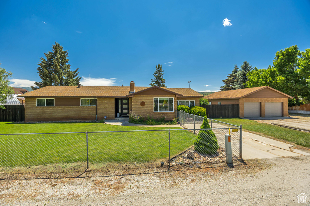 Ranch-style house featuring brick siding, a fenced front yard, a chimney, and driveway