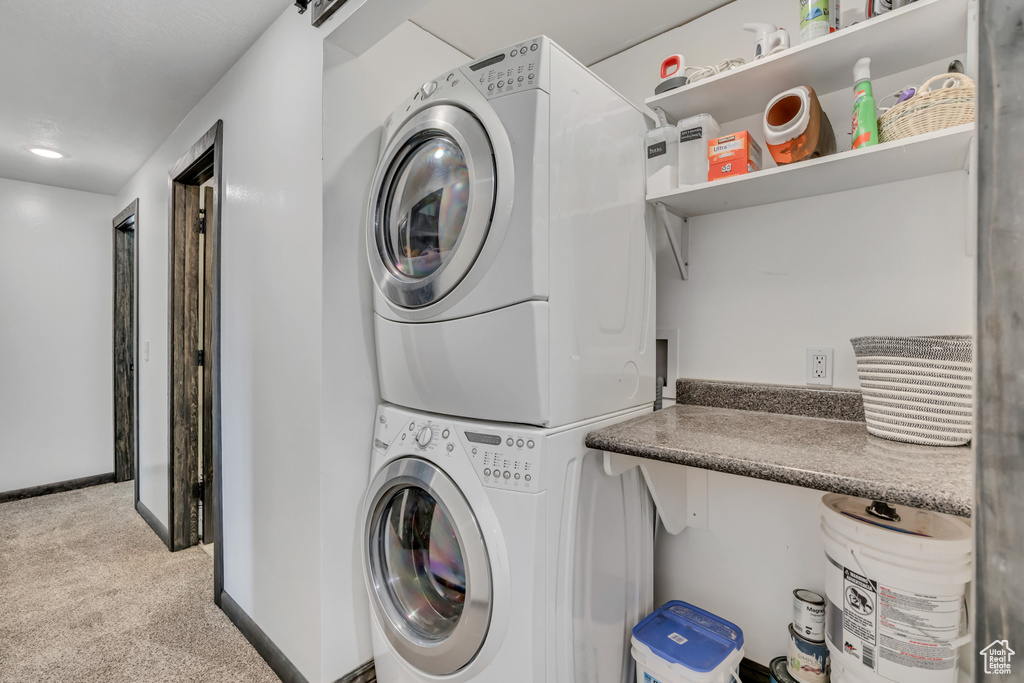 Laundry room featuring stacked washer / drying machine and carpet flooring