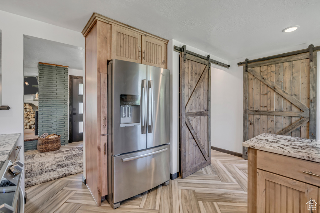 Kitchen featuring appliances with stainless steel finishes, a barn door, light brown cabinets, and recessed lighting