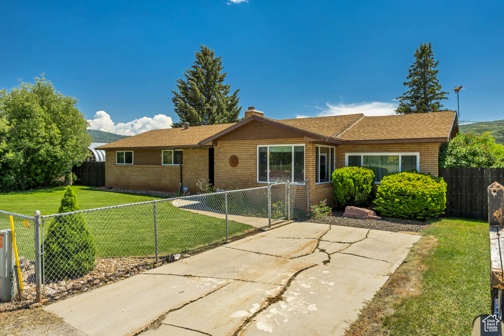 Ranch-style house featuring brick siding, a fenced backyard, a chimney, and a patio